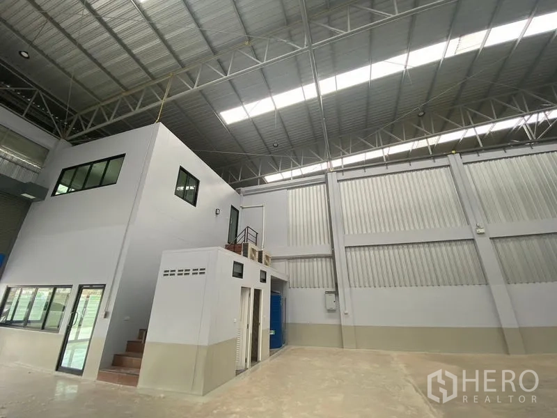 Warehouse for rent in Pathum Thani - Interior angle showing mezzanine office, restrooms, and corrugated metal wall panels.