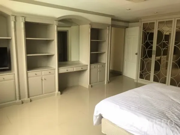 公寓 出租在Watthana, Bangkok - 主卧内置衣柜与开放书架、梳妆台，浅色地砖。