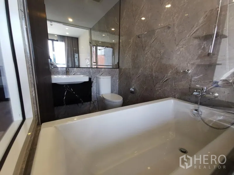 Condominium for rent or sale in Watthana, Bangkok - Marble en‑suite bathroom with large soaking tub, vanity and toilet.