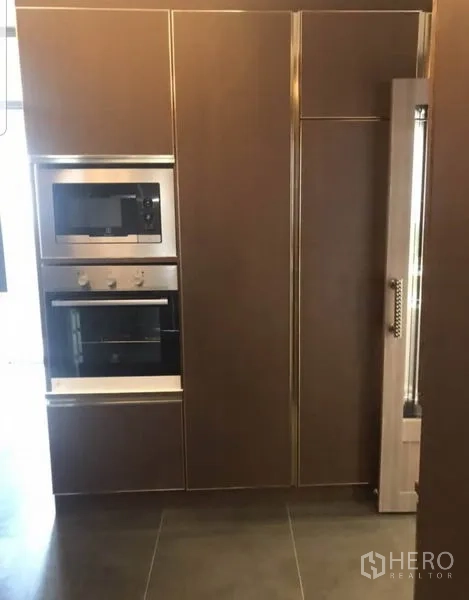 Condominium for rent in Khlong Toei, Bangkok - Sleek kitchen wall with built-in microwave, oven and tall pantry.