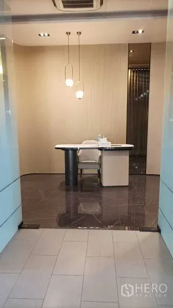 Retail Space for rent - Modern retail reception with marble floor, pendant lights and a sleek desk viewed through glass doors.