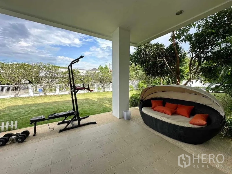 Detached House for rent or sale in Bang Phli, Samut Prakan - Covered patio with exercise equipment and daybed overlooking the garden