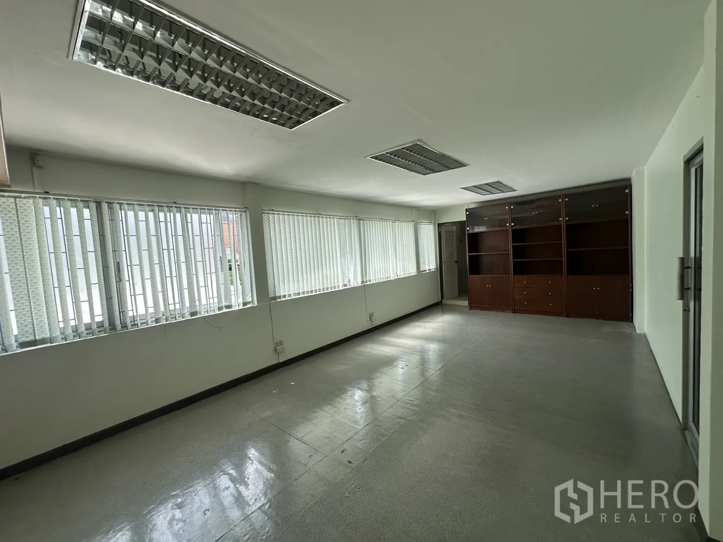 Retail Space for rent in Watthana, Bangkok - Long office room with window wall and dark wood shelving units.