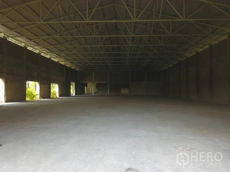 Factory for sale in Samut Prakan - Wide shot of an empty warehouse with high ceiling and multiple openings for light and access.
