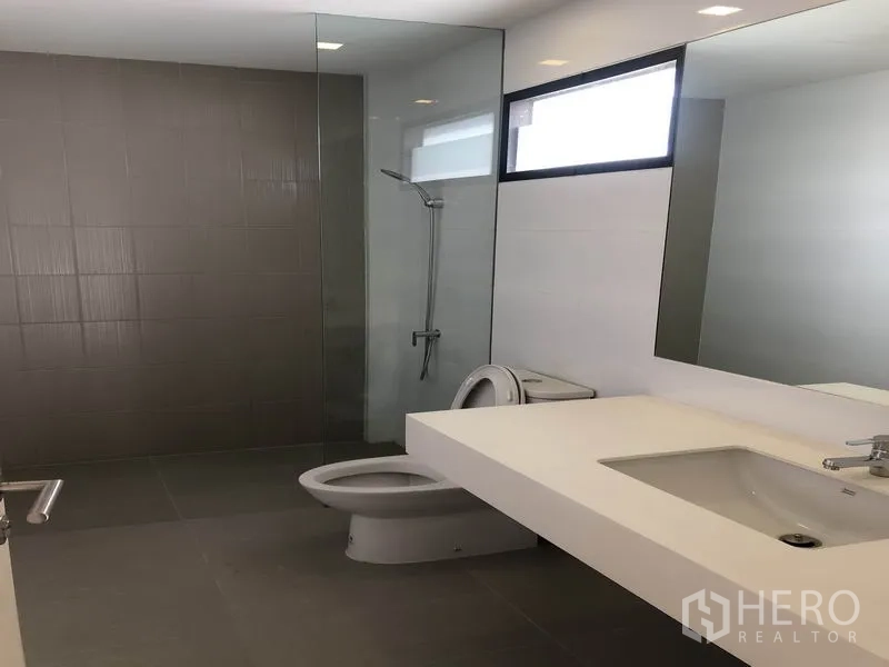 Townhouse for rent in Saphan Sung, Bangkok - Modern bathroom with long vanity, glass-enclosed shower and gray floor tiles