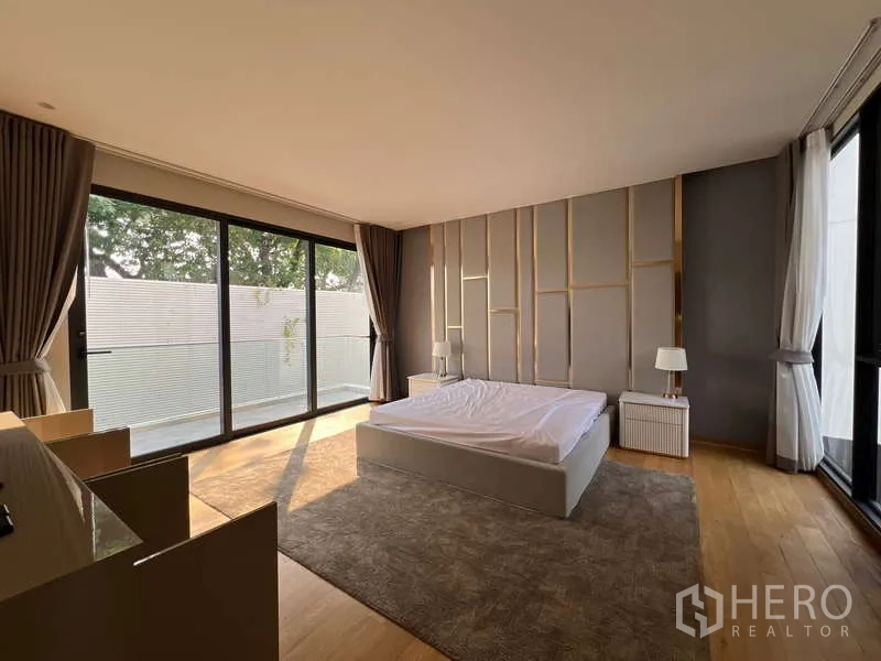 Detached House for rent in Suan Luang, Bangkok - Spacious primary bedroom with wood floors and full‑height glass doors.