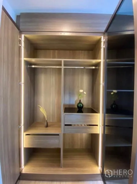 Condominium for rent or sale in Phaya Thai, Bangkok - Open illuminated wooden wardrobe with drawers and hanging rails.