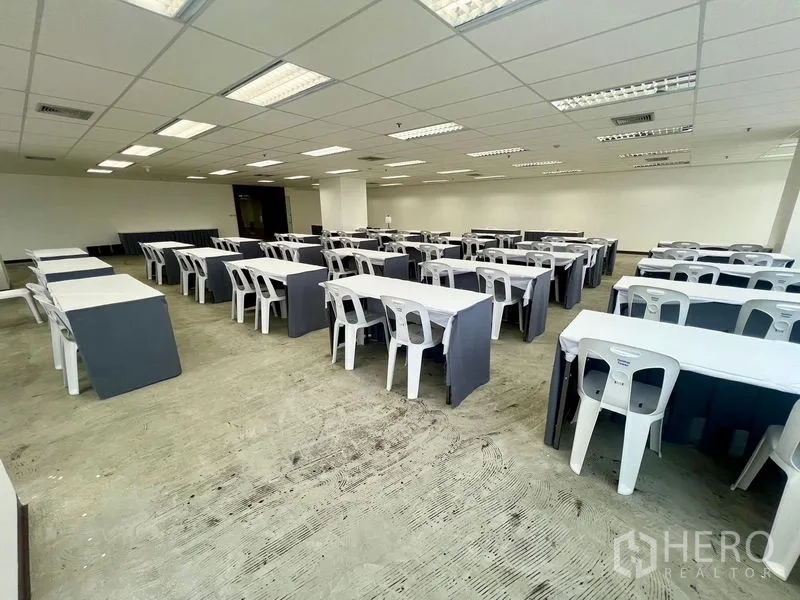 Office Space for rent - Rear-corner view of a large training room layout with AC vents in the ceiling and wide windows for natural light.