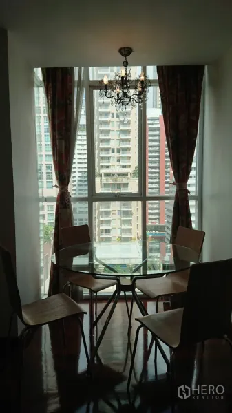 公寓 出租在Pathum Wan, Bangkok - 餐区设有圆形玻璃餐桌和四把椅子，吊灯下临近大窗户，可眺望高楼。