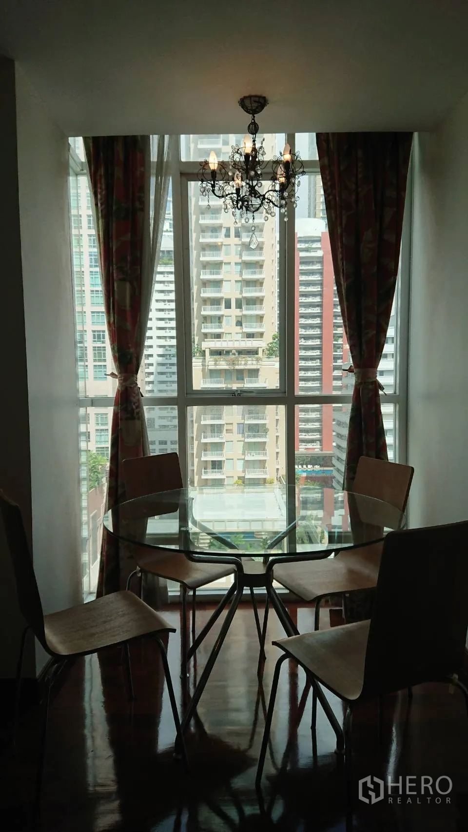 公寓 出租在Pathum Wan, Bangkok - 餐区设有圆形玻璃餐桌和四把椅子，吊灯下临近大窗户，可眺望高楼。