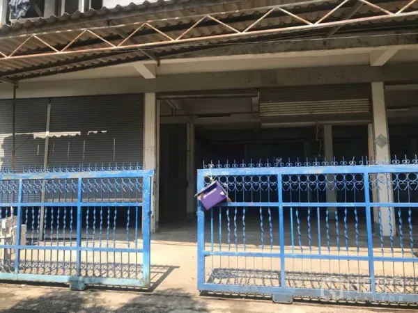 Warehouse for rent in Bueng Kum, Bangkok - Front exterior of the warehouse with blue metal gate, roller shutters and a covered loading area.