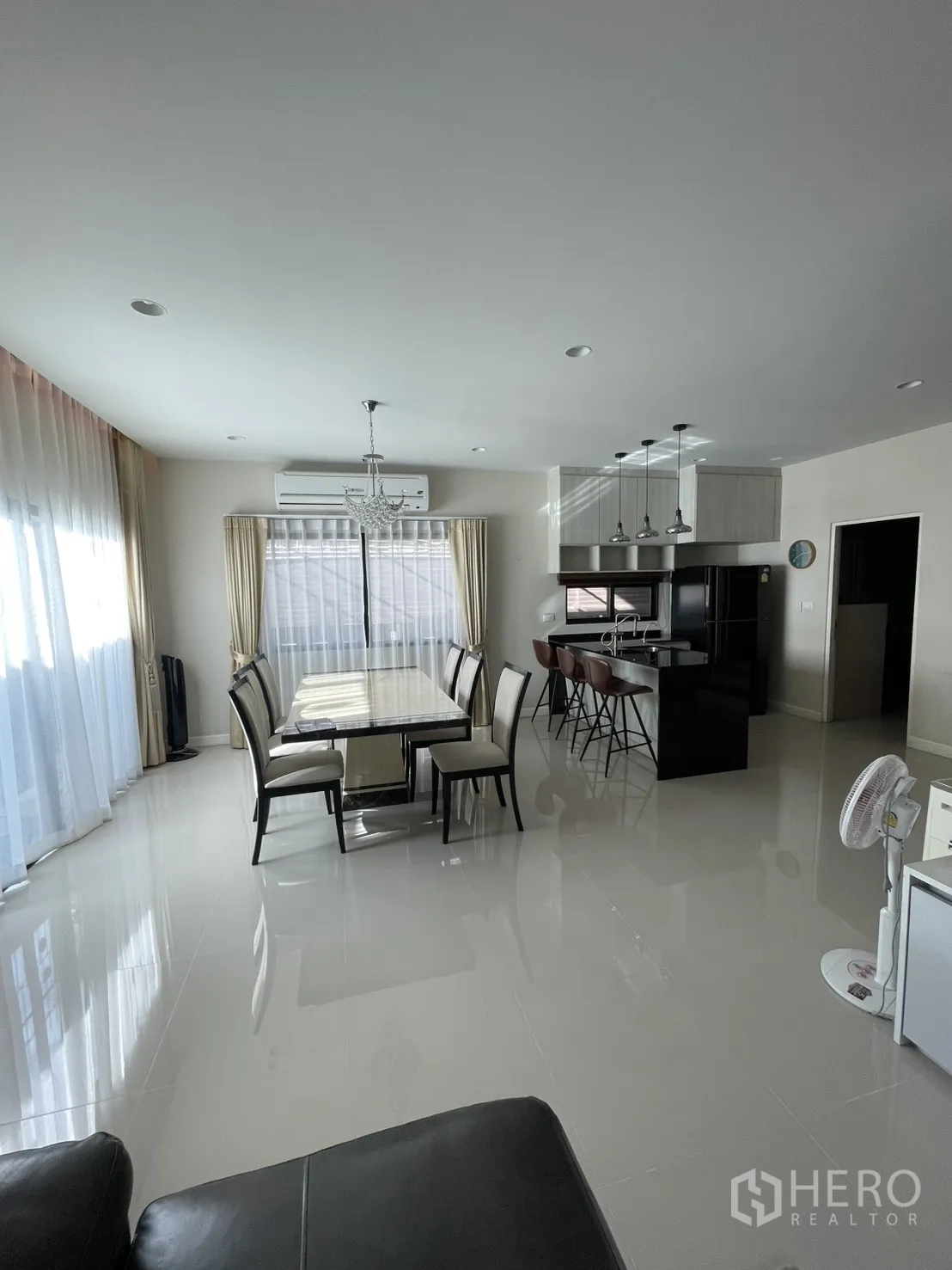 Detached House for rent or sale in Lam Luk Ka, Pathum Thani - Open-plan dining and kitchen area with chandelier, island counter and full-height windows.