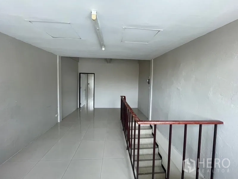 Shophouse for rent in Phra Khanong, Bangkok - Upper floor open room with glossy tiles and a stairwell railing.