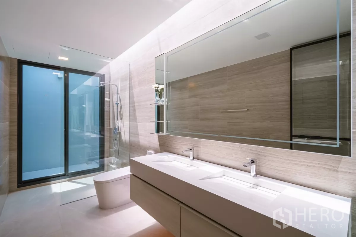 Detached House for rent or sale in Saphan Sung, Bangkok - Contemporary bathroom with double vanity, large mirror and glass shower.