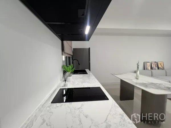 Townhouse for rent in Bang Phli, Samut Prakan - Modern kitchen featuring marble-look counters, induction hobs, sink and dining island.