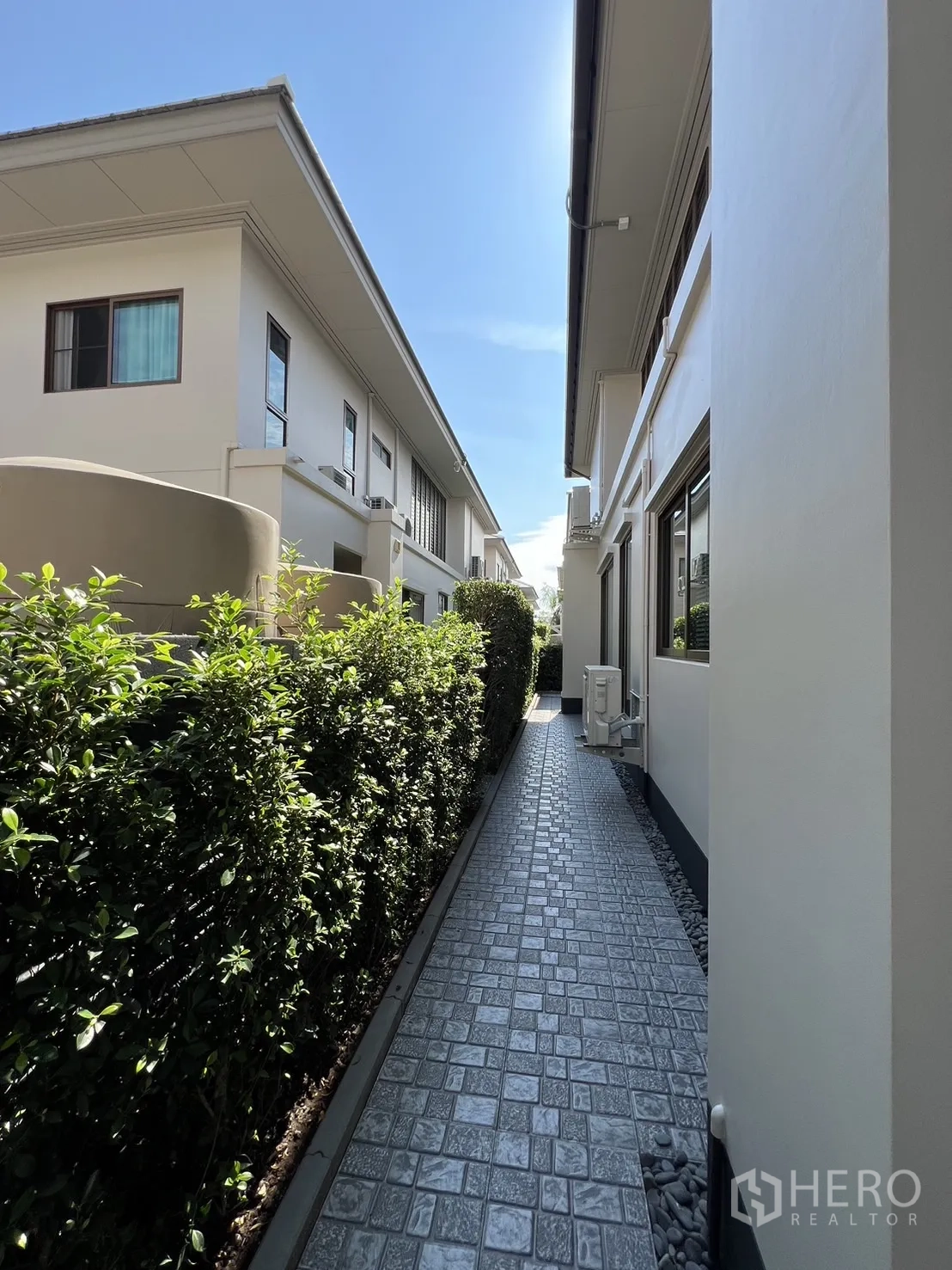 独立式住宅 出租或出售在Bang Kapi, Bangkok - 房屋之间的服务步道，石纹地面与修剪整齐的绿篱。