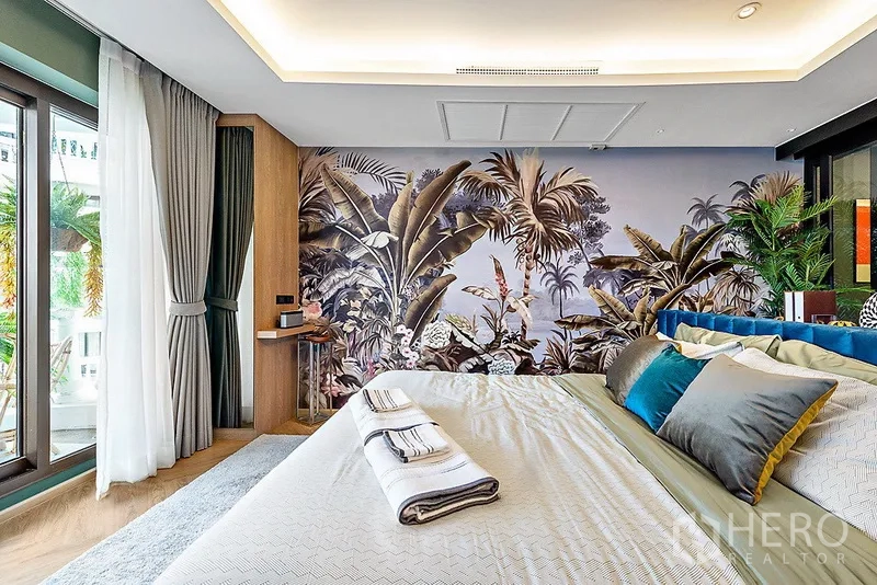 Condominium for rent in Bang Rak, Bangkok - Master bedroom with king bed, tropical feature wall, floor-to-ceiling windows, and access to a balcony with greenery.
