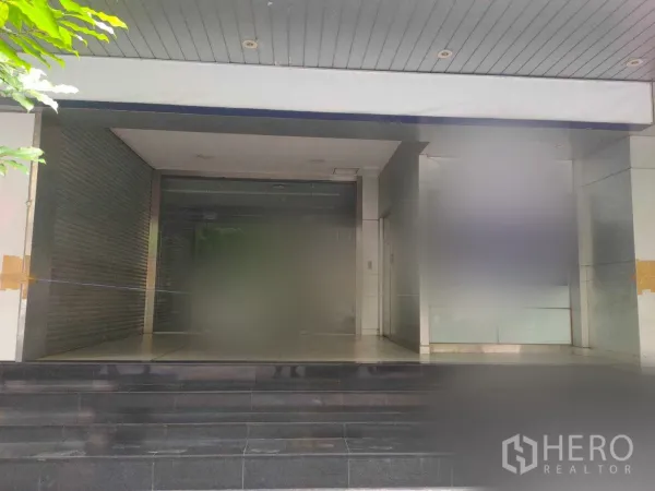 สำนักงาน ให้เช่าในYan Nawa, Bangkok - ทางเข้าอาคารสำนักงานพร้อมประตูกระจก บันไดหินสีเข้ม และช่องม้วนปิดด้านข้าง ในกรุงเทพฯ
