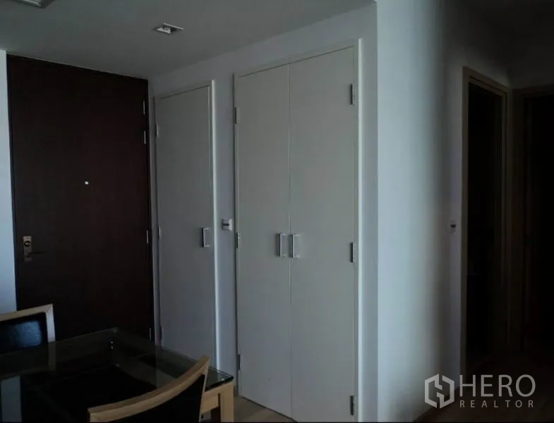 Condominium for rent in Khlong Toei, Bangkok - Entry area with dark main door, white storage closets, and a dining corner.