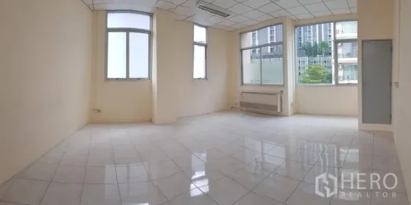 Office Space for rent in Phra Khanong, Bangkok - Panoramic view of a spacious 50 sqm office featuring big windows on two sides, grid ceiling, and fluorescent lighting.