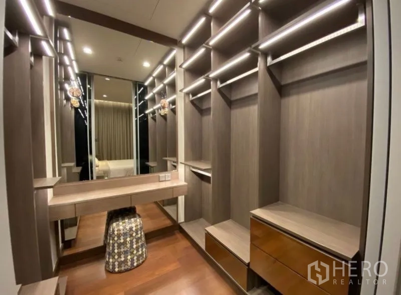 Condominium for rent in Khlong Toei, Bangkok - Luxury walk-in closet with illuminated shelving, vanity and wood flooring.