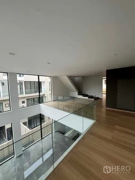 带办公室的家 出租或出售在Lat Phrao, Bangkok - 夹层层面配玻璃栏杆，俯瞰挑高中庭与楼梯。