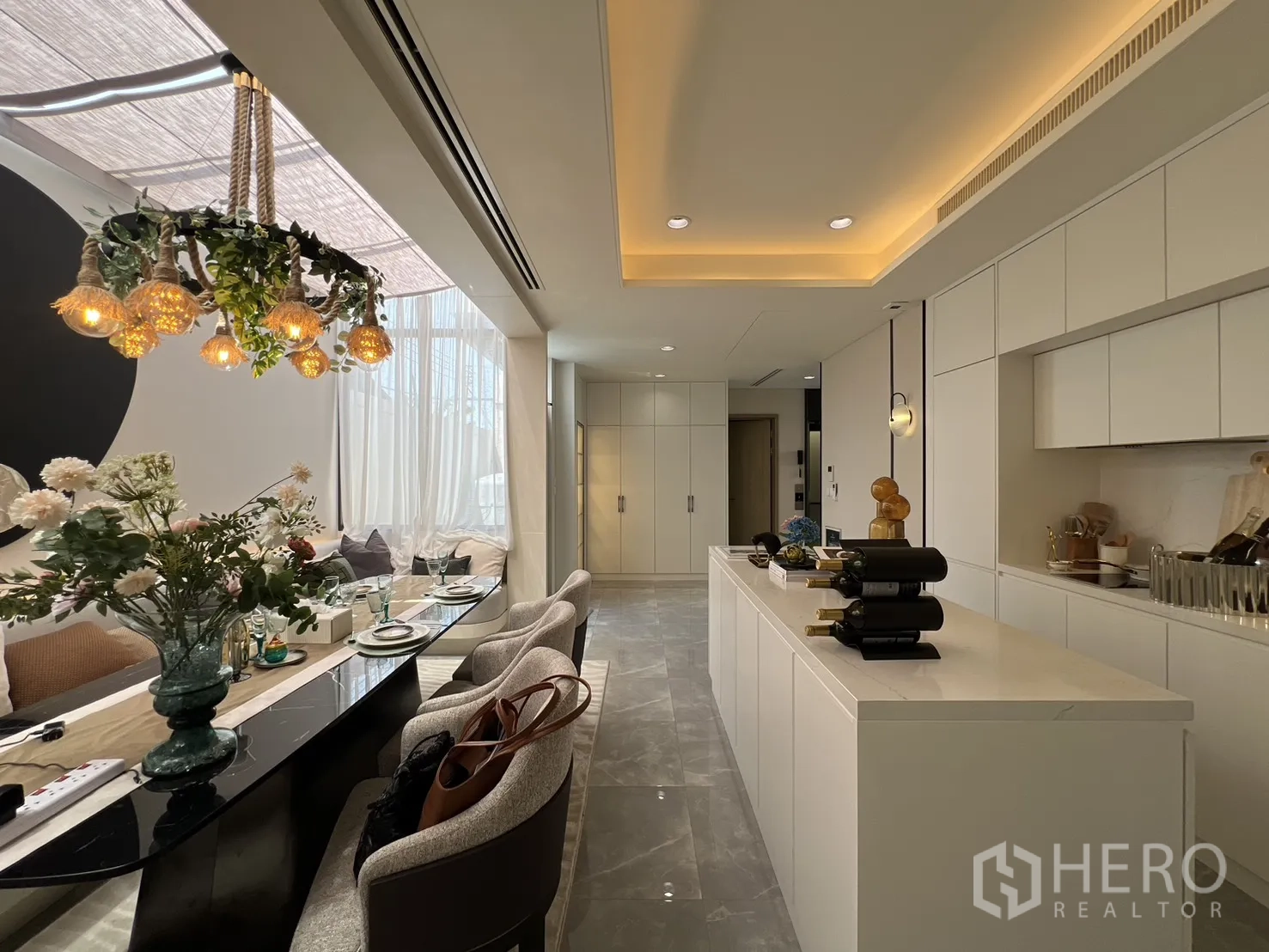 Semi-detached House for sale in Yan Nawa, Bangkok - Kitchen island opposite full-height cabinets and dining table setting.