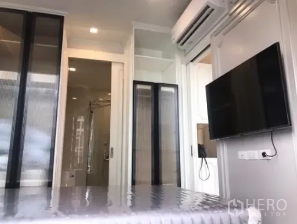 Condominium for rent in Watthana, Bangkok - Bedroom view toward glass-enclosed shower bathroom, wardrobes and wall-mounted TV