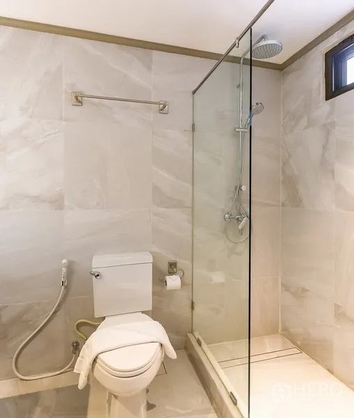 Apartment for rent in Khlong Toei, Bangkok - Modern bathroom with glass-enclosed shower, rain showerhead, and bidet spray.