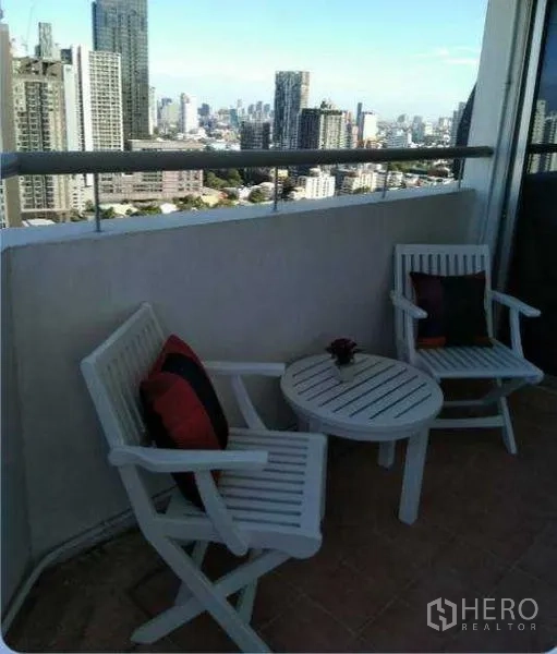 Condominium for rent in Khlong Toei, Bangkok - Private balcony with two chairs and a table overlooking the Bangkok skyline.