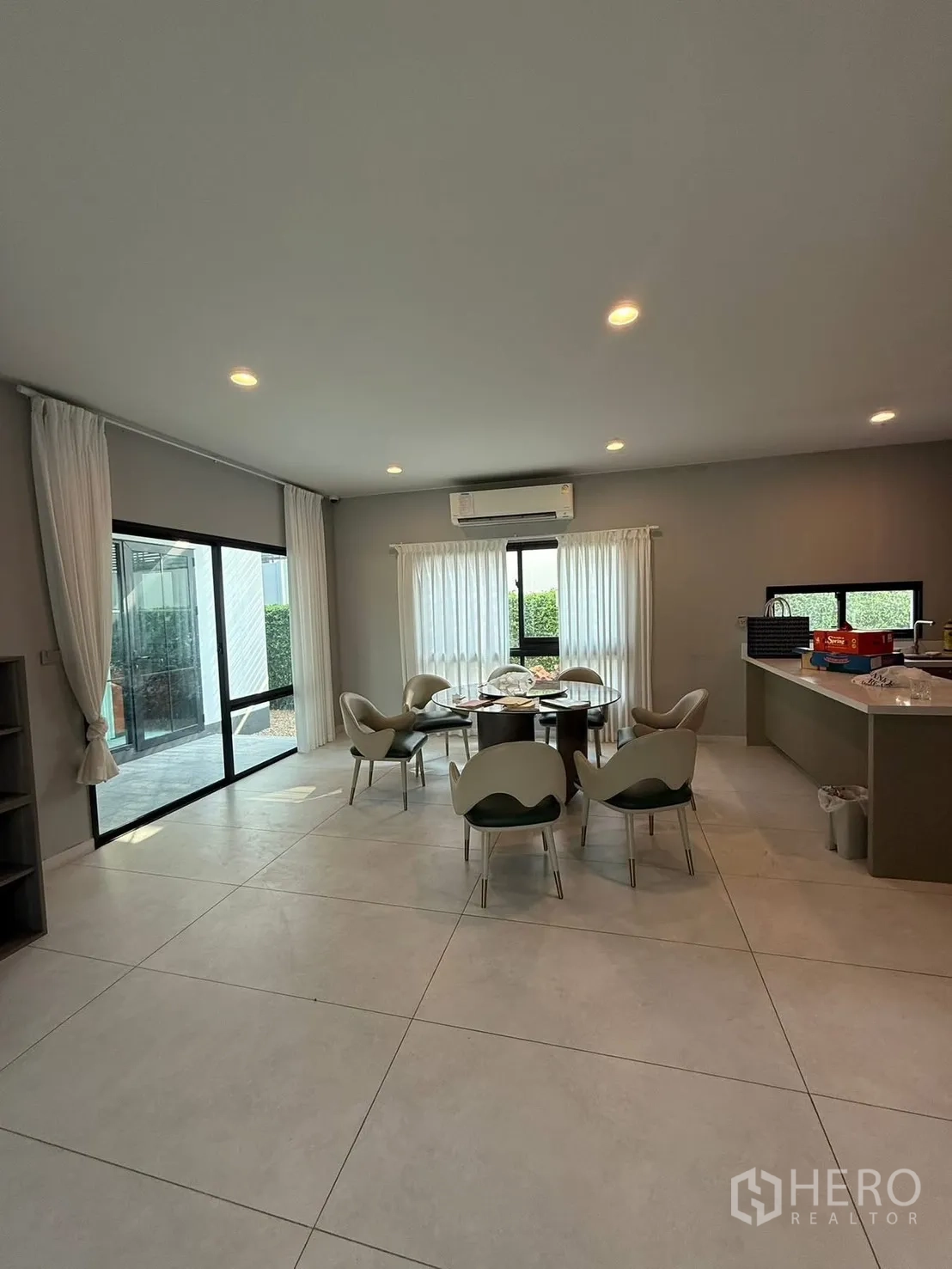 独栋房屋 for rent in Bang Kapi, Bangkok - 开放式餐起居一体区，圆餐桌，大块地砖与推拉玻璃门。