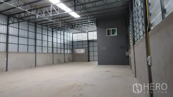 Warehouse for rent in Lam Luk Ka, Pathum Thani - Spacious warehouse interior with high ceiling, steel trusses, skylight panels and smooth concrete floor.
