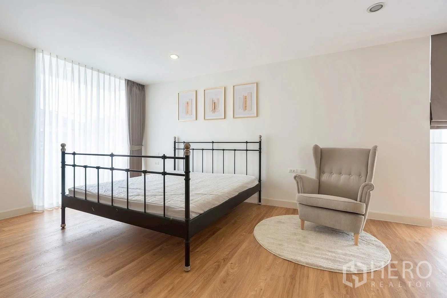 Detached House for rent in Saphan Sung, Bangkok - Guest bedroom with metal bed frame and cozy wingback chair.