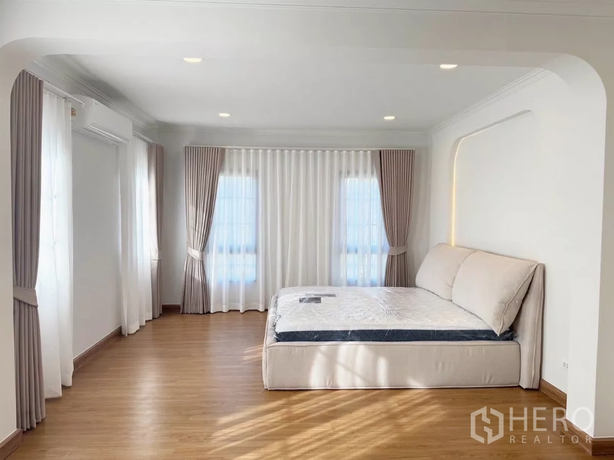 Detached House for rent or sale in Bang Phli, Samut Prakan - Spacious master bedroom with large windows, wood floor and upholstered bed.