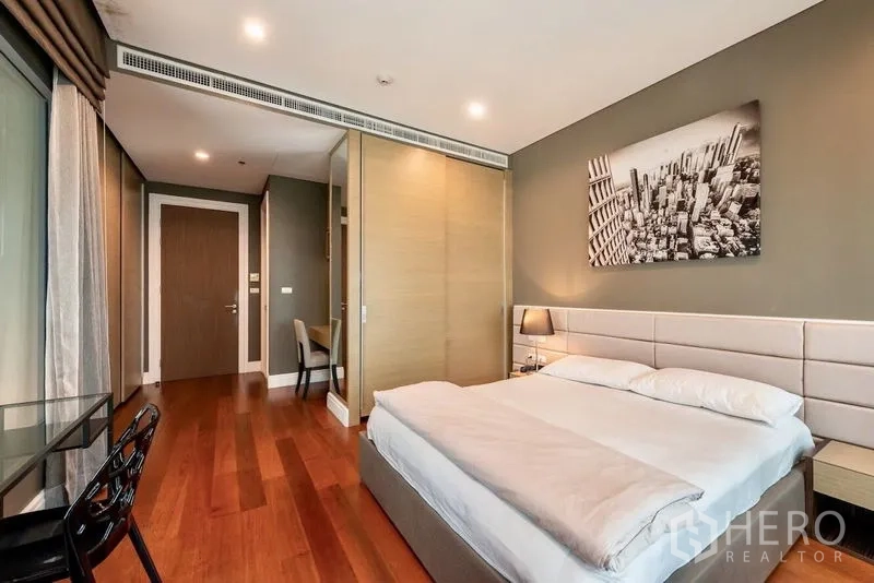 Condominium for rent in Khlong Toei, Bangkok - Cozy bedroom with sliding wardrobe and city-facing windows.