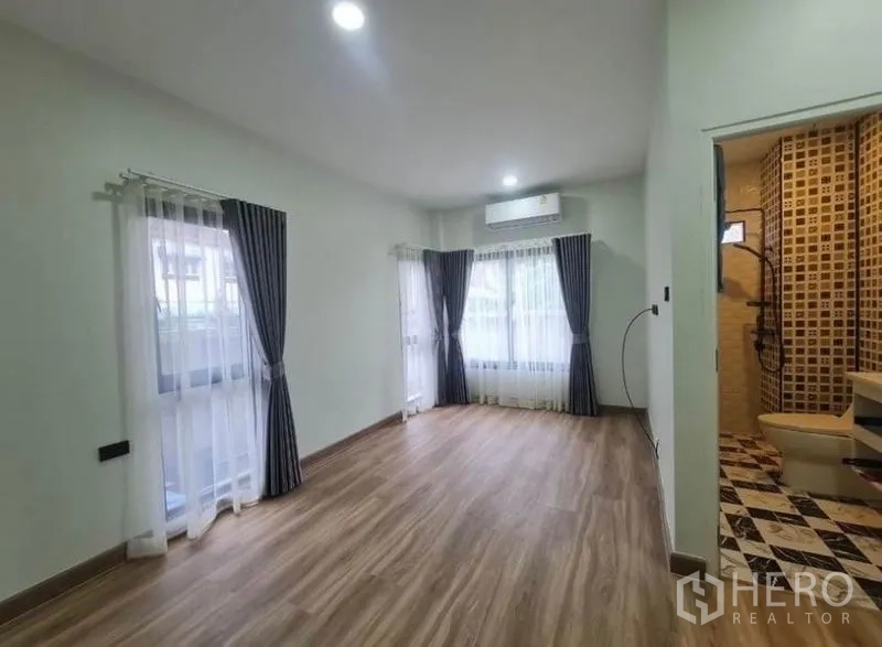 Detached House for sale in Sai Mai, Bangkok - Airy bedroom with wood flooring, multiple windows, and an ensuite bathroom.