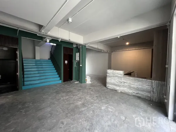 带办公室的家 出租在Pathum Wan, Bangkok - 一层开放空间，青绿色楼梯、裸露天花与石材接待台。