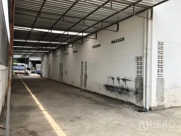 Factory for rent in Nonthaburi - Covered loading bay with a metal roof and through-lane next to the warehouse.