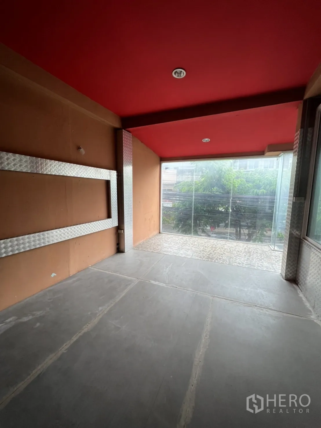 Shophouse for rent in Watthana, Bangkok - Corner space with red ceiling, aluminum-framed window and metallic wall accents.