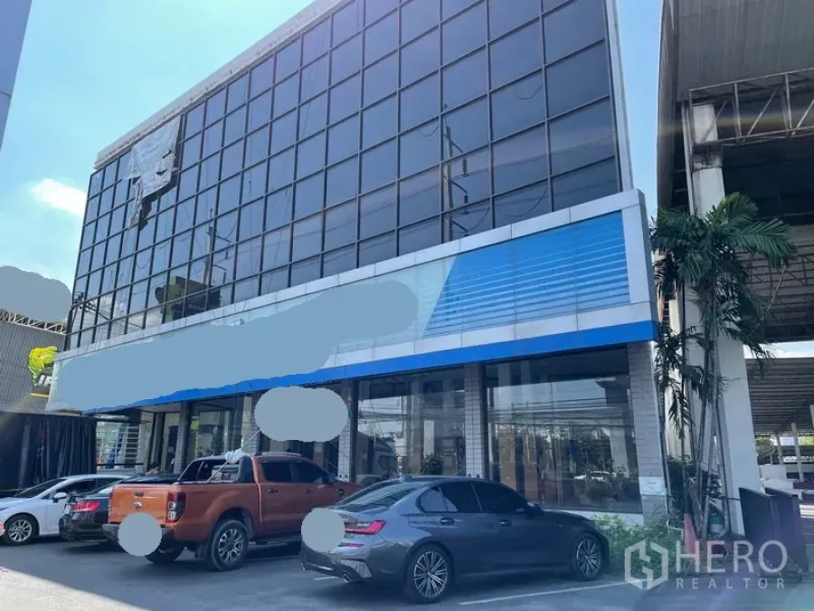 Warehouse for rent in Prawet, Bangkok - Glass-front commercial building facade with on-site parking spaces.