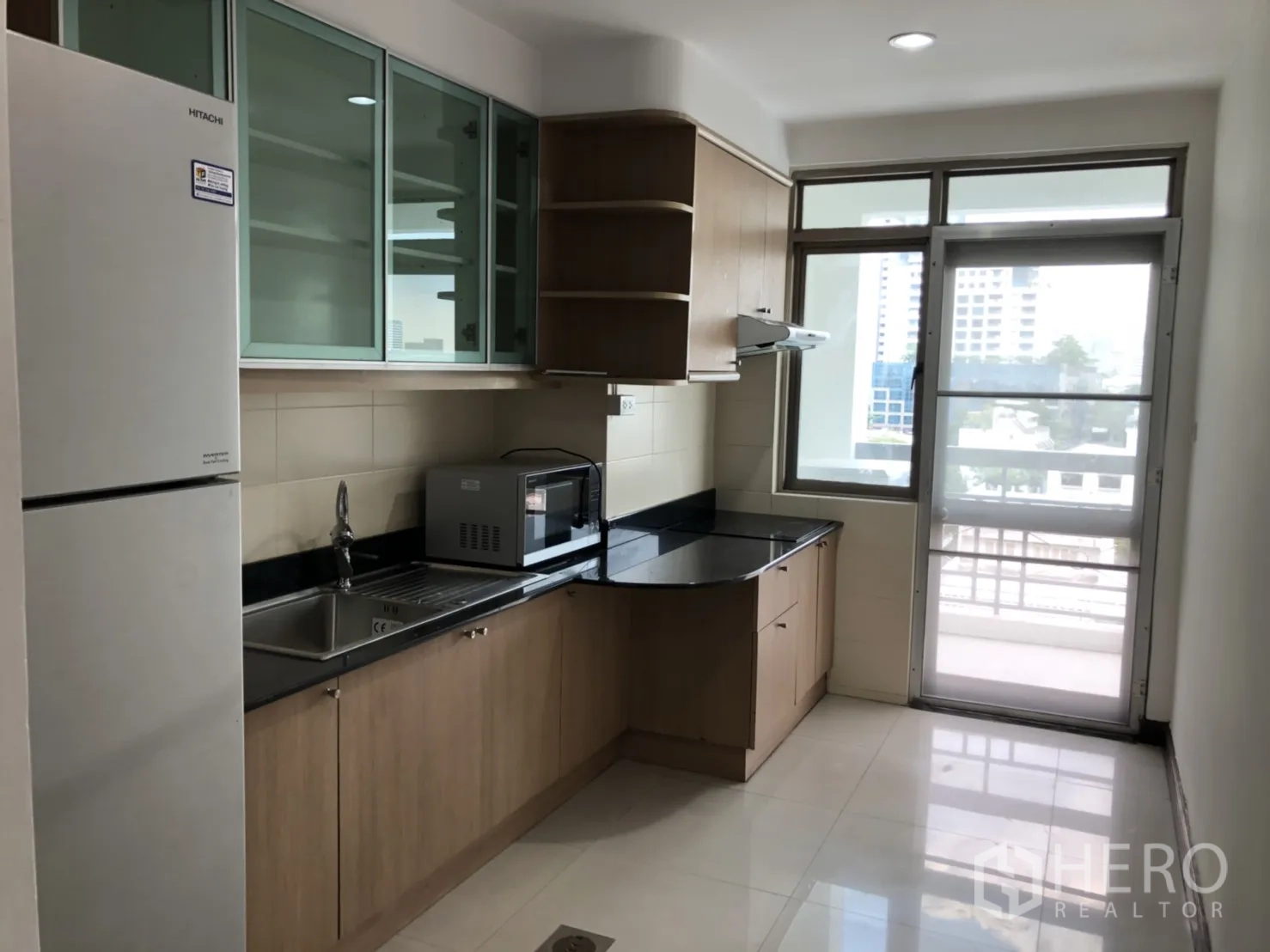 Condominium for rent in Watthana, Bangkok - Kitchen with fridge, microwave and glass-front cabinets.