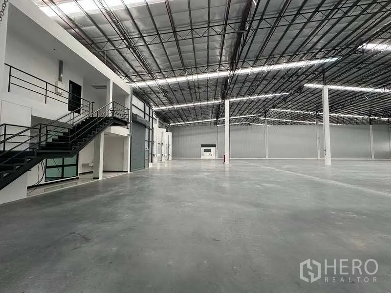 Warehouse for rent in Bang Phli, Samut Prakan - Warehouse floor showing mezzanine office, staircase and large roller shutter door.