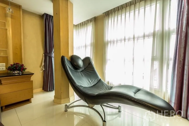 Retail Space for rent - Sunlit corner with a modern black chaise lounge beside floor-to-ceiling curtains.