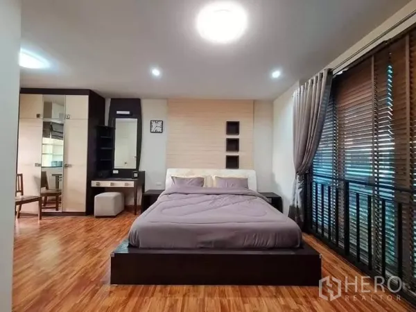 Townhouse for rent in Khlong Toei, Bangkok - Spacious master bedroom with wood flooring, large windows with blinds and curtains, dressing table and wardrobes.