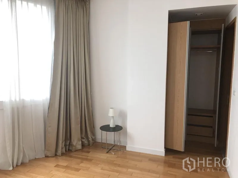 Condominium for rent in Khlong Toei, Bangkok - Cozy bedroom corner with large window, full drapes, side table and open wardrobe.