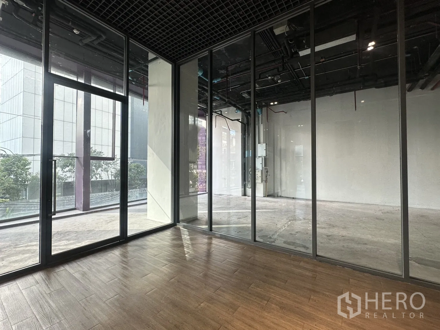 零售空间 for rent in Khlong Toei, Bangkok - 带木纹地面的玻璃隔间，面向主零售大厅。