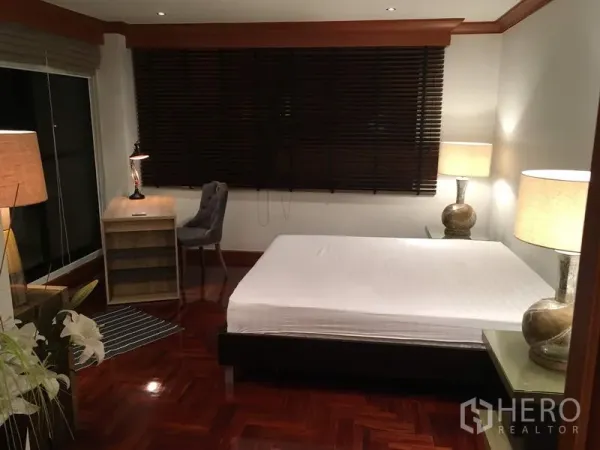 Condominium for rent in Sathon, Bangkok - Primary bedroom with double bed, desk, bedside lamps, dark blinds and polished wood flooring.