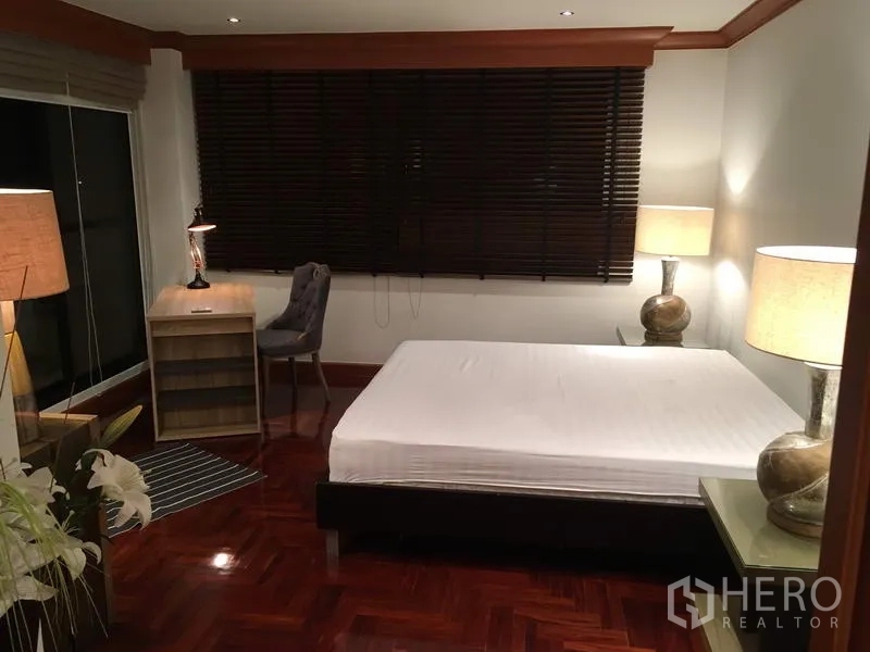 Condominium for rent in Sathon, Bangkok - Primary bedroom with double bed, desk, bedside lamps, dark blinds and polished wood flooring.