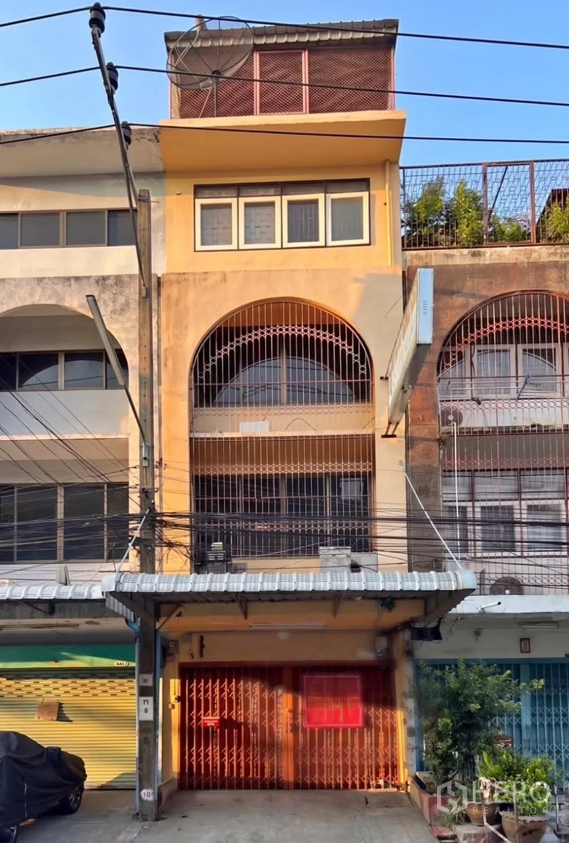 店屋 for rent in Suan Luang, Bangkok - 临街店屋立面，带卷帘门与拱形窗格。