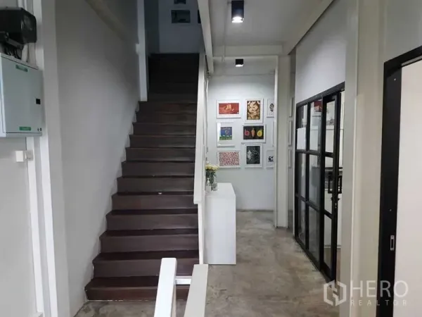 Shophouse for sale in Bang Rak, Bangkok - Interior hallway with wooden staircase, concrete floor and glass-partitioned office.